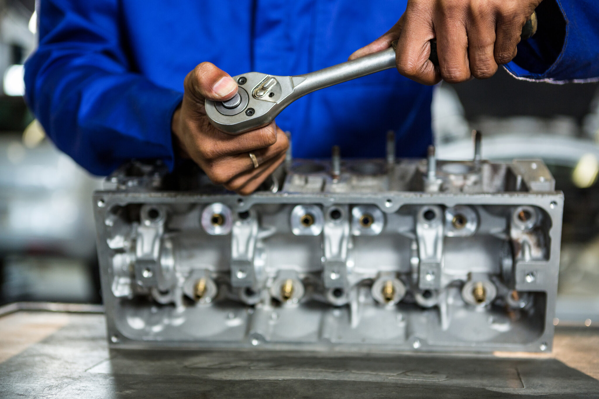 Mid-section of mechanic repairing engine part with ratchet at the repair garage